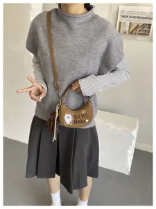Vue portée d’un sac demi-lune marron effet daim, brodé d’un ours, avec cœurs et breloque en peluche