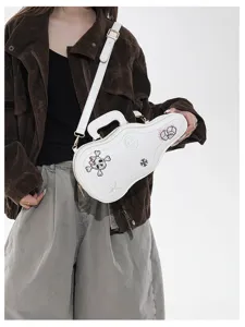 Sac blanc en forme de guitare porté en bandoulière, avec des motifs de crâne, dés, étoile et fleurs