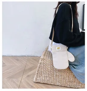 Vue portée d’un sac ivoire en velours côtelé, bordé de tissu doux, près d’un siège tressé