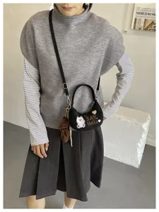 Porté avec une tenue grise, mini-sac noir brodé d’un ours, avec « SAY Hello » et un charm en peluche