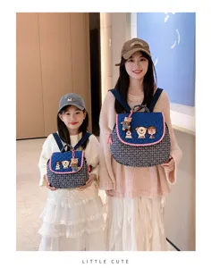 Mère et fille portent des sacs à dos bleus matelassés assortis, ornés de motifs ludiques, en intérieur