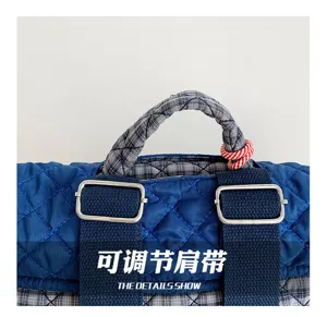 Détail du tissu matelassé bleu, de la poignée à carreaux et de la sangle réglable à boucle métal