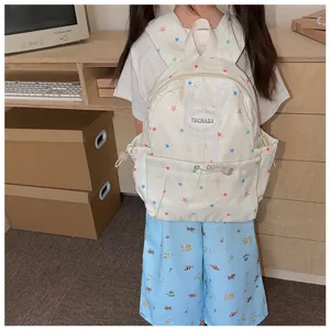 Enfant portant un sac à dos crème à étoiles colorées, avec poche avant et logo ovale