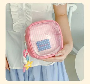 Pochette rose tenue en main, avec fenêtre transparente, doublure à carreaux et breloque étoile
