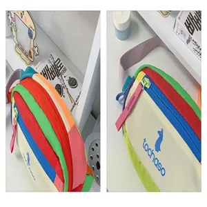 Gros plan sur les panneaux colorés, la fermeture éclair, la sangle rose et le clip du sac