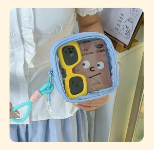 Pochette transparente bleu clair tenue en main, avec zip, cordons tressés, lunettes jaunes et carte