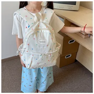 Enfant portant un sac à dos ivoire à étoiles colorées, avec une poche avant zippée