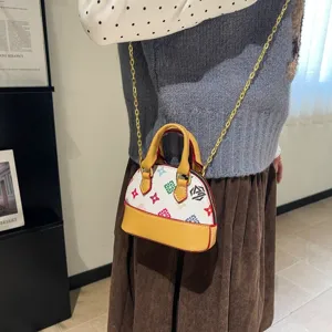 Vue portée d’un sac coquillage blanc à imprimé losanges colorés, bord jaune et chaîne dorée