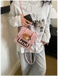 Vue portée d’un sac rose à pois, avec pendentif ourson et lettres MINI en peluche