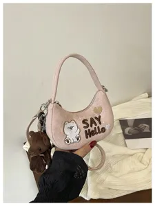 Détail d’un sac rose en demi-lune avec breloque ourson, broderie « SAY Hello » et cœur décoratif