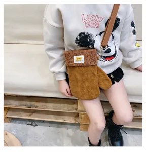 Une personne porte un sac marron en velours côtelé, en forme de moufle, avec bordure en peluche