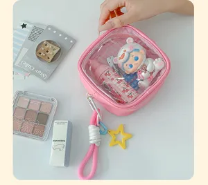 Vue de dessus d’une pochette rose à fenêtre claire, contenu visible, dragonne et breloque étoile