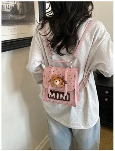 Vue de dos montrant un mini sac à dos rose à pois, avec un ours en peluche et le texte MINI