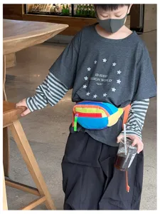 Enfant portant une banane multicolore vive sur un haut superposé, dans un décor de café décontracté
