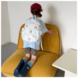 Vue de dos d’un enfant portant un sac à carreaux bleu clair orné de pommes rouges et d’étoiles