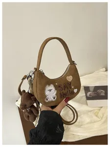 Sac demi-lune marron présenté à la main, avec broderie d’ours, cœur et pendentif en peluche assorti