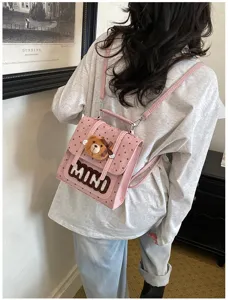 Vue arrière du sac rose à pois porté, avec un ourson suspendu et le mot MINI en relief
