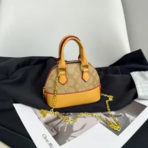 Détail d’un sac coquillage beige à motif, avec bordure jaune, liseré rouge et chaîne dorée