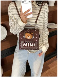 Photo de tenue avec mini sac marron à pois, pendentif ours et inscription MINI bien visible