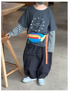 Enfant portant une banane colorblock arc-en-ciel sur une tenue décontractée superposée, en pied