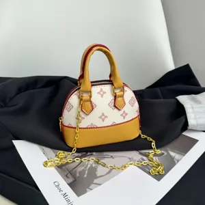 Détail du sac bombé à motif crème, avec base jaune, bordure rouge et chaîne d’épaule dorée