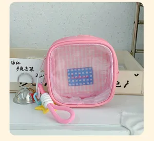 Détail d’une pochette rose à fenêtre transparente, doublure à carreaux et dragonne colorée