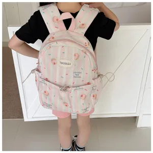Enfant portant un sac à dos rose rayé aux motifs de cupcakes et cerises, vu de face