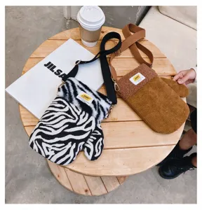 Vue de dessus de deux sacs, l’un en peluche zébrée, l’autre en velours côtelé brun, sur table en bois