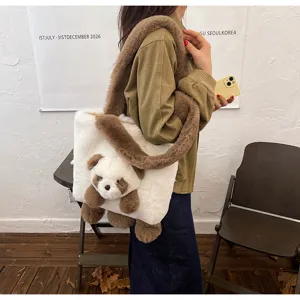 Porté à l’épaule, sac blanc en peluche avec bordure brune et pendentif ourson visible