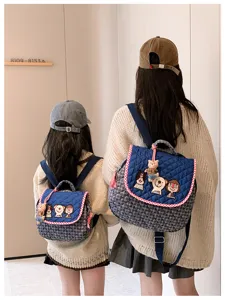 Deux personnes de dos portent des sacs bleus matelassés assortis, brodés et ornés de breloques ours