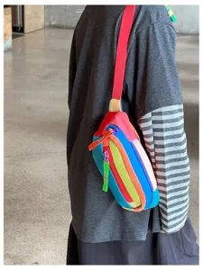 Vue de profil d’une personne portant une petite sacoche multicolore à bandoulière rouge vif