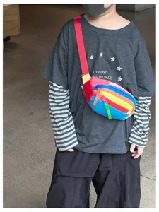 Enfant portant un sac bandoulière aux bandes arc-en-ciel, avec sangle rouge et fermetures colorées