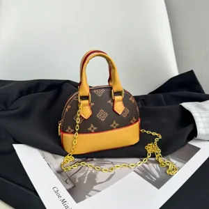Détail d’un mini-sac à motifs bruns, avec panneaux jaunes, bordure rouge et chaîne dorée