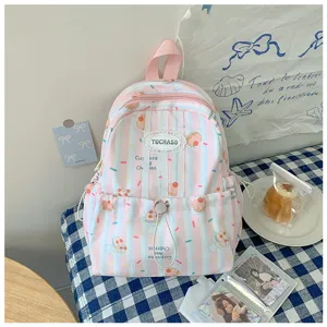 Vue du sac à dos rose rayé, orné de gâteaux et de cerises, avec fermeture éclair et médaillon rond