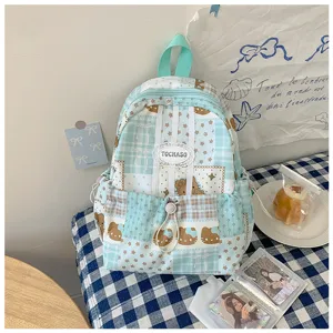 Vue détaillée d’un sac à dos bleu pâle avec empiècements à carreaux, étoiles et motifs d’ours