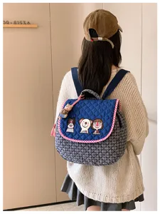 Sac matelassé bleu marine vu de dos, broderie cartoon, bordure rouge et blanche et breloque ours