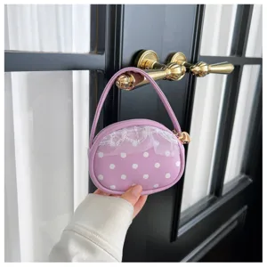 Détail d’un petit sac parme à pois blancs, avec bordure en dentelle et anse arrondie