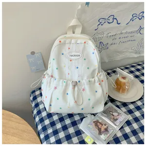 Détail d’un sac blanc à étoiles colorées, avec bordure rayée et poche froncée à cordon