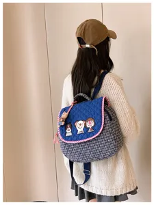 Vue de dos d’un sac à dos matelassé bleu à carreaux, avec broderie fantaisie et petit ours suspendu
