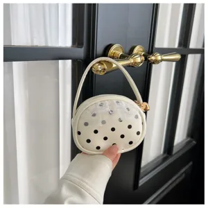 Détail du sac rond crème à pois noirs, avec résille blanche et petit pendentif cœur doré