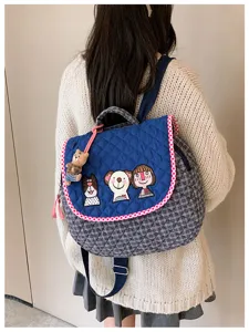 Vue de dos d’un sac bleu matelassé avec écussons illustrés, bordure à carreaux et breloque ourson.