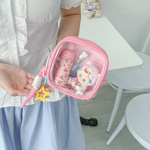 Trousse rose en PVC transparent, avec dragonne et breloque étoile, tenue en main avec son contenu
