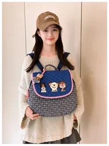 Modèle portant un sac à dos matelassé bleu marine, brodé de personnages, avec bord rouge et blanc