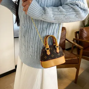 Petit sac à main en PU brun à monogramme, bordure beige et chaîne dorée, porté à l'épaule