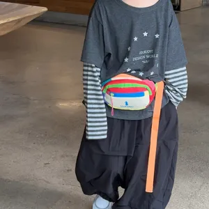 Enfant portant une banane légère en toile Oxford, avec des empiècements colorés et une sangle orange