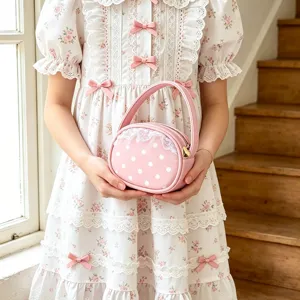 Petit sac rond rose à pois blancs et bordure en dentelle, tenu par un modèle à la lumière naturelle