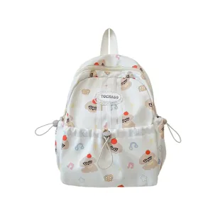 Sac à dos enfant blanc en nylon, imprimé de dessins ludiques, vu de face avec poches latérales