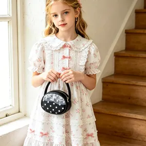 Petit sac rond noir en PU à pois blancs et bordure en dentelle, porté avec une robe fleurie
