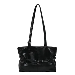 Schwarze Kunstleder-Schultertasche mit Nietenriemen und Schnallengurt, frontal auf weißem Grund