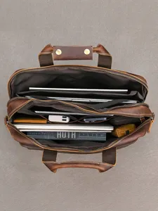 Borsa da lavoro aperta in pelle marrone, vista dall’alto, con laptop e documenti negli scomparti
